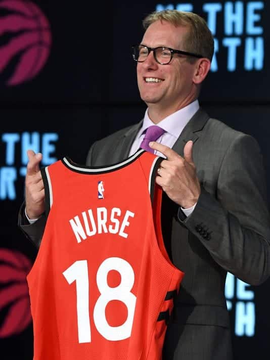 Nick Nurse holding up a jersey signifying he's become the Toronto Raptors next head coach.