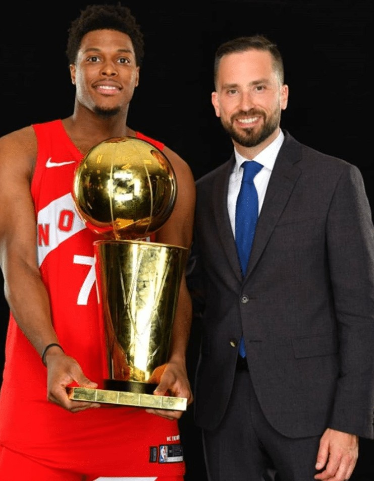 Eric Smith posing with the Larry O'Brien NBA Championship trophy after the Toronto Raptors won in 2019. Kyle Lowry is in the photo as well.
