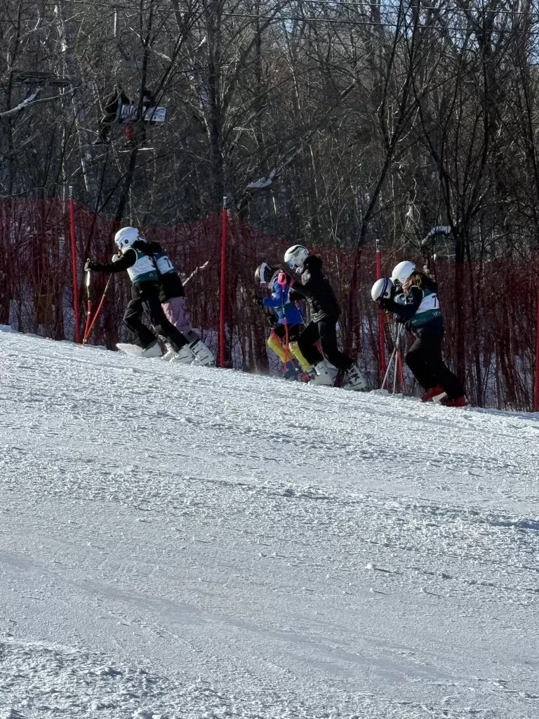 Ski NB athletes walk across the snow.