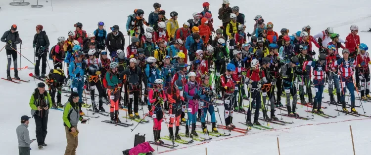 Ski mountaineering participants gathered at a snowy race venue.