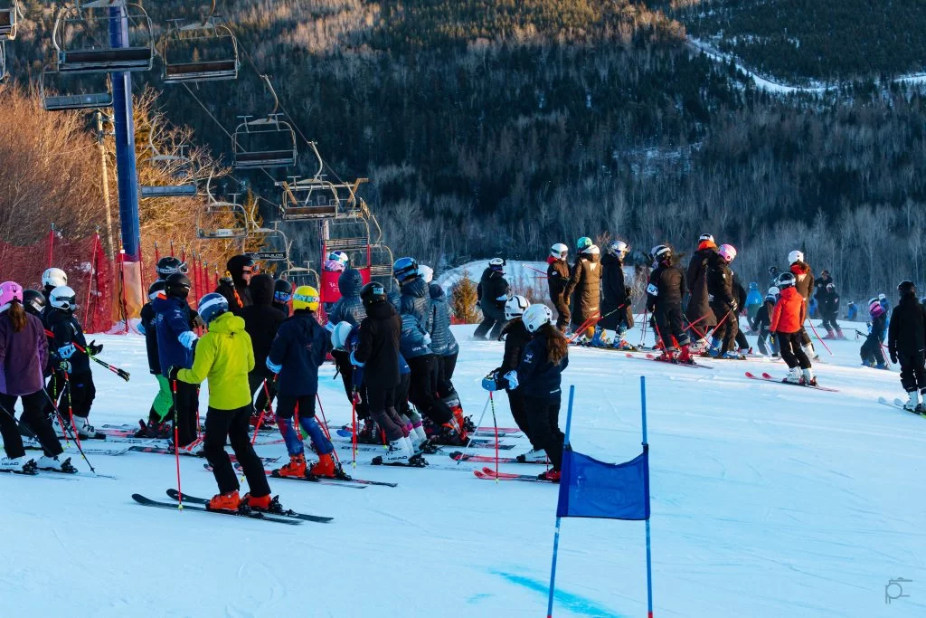 Young athletes and coaches gather on a ski hill.